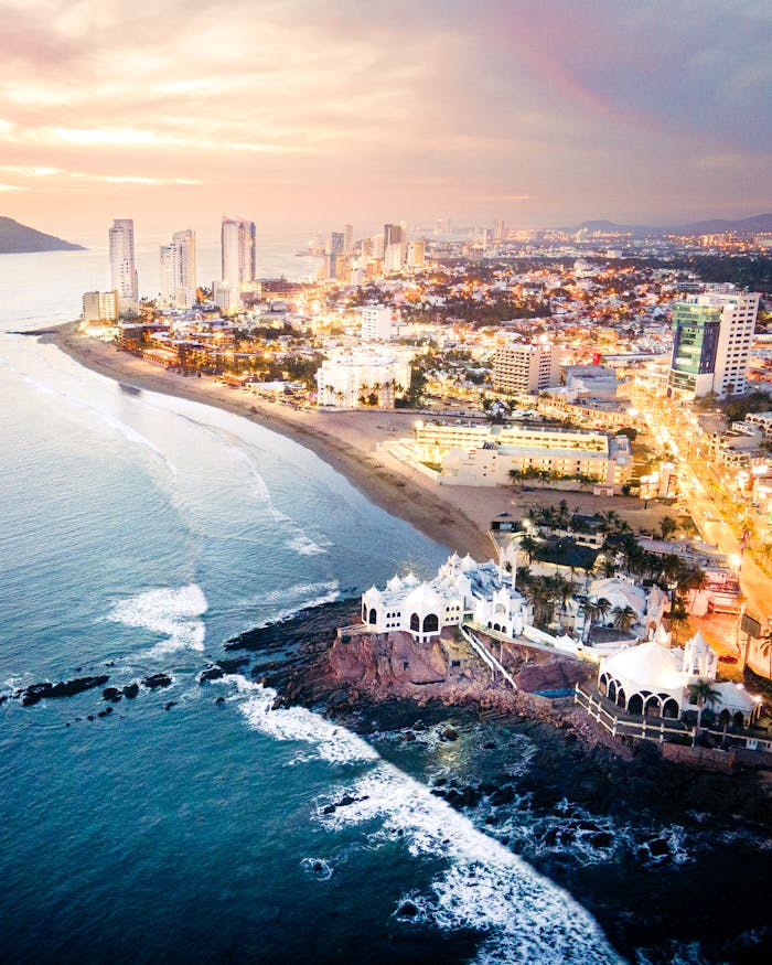 Stunning aerial view of Mazatlán's illuminated coastline at sunset with vibrant cityscape and coastal beauty.