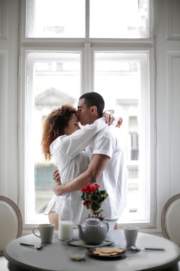 A loving couple shares an intimate moment by a window, creating a serene and romantic ambiance.