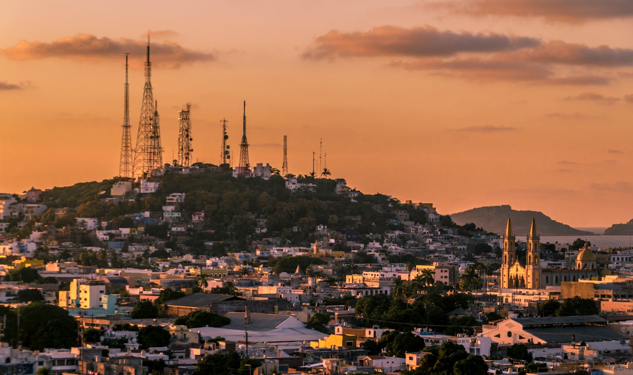 A breathtaking view of Mazatlán's skyline and cathedral at sunset with vibrant orange hues.